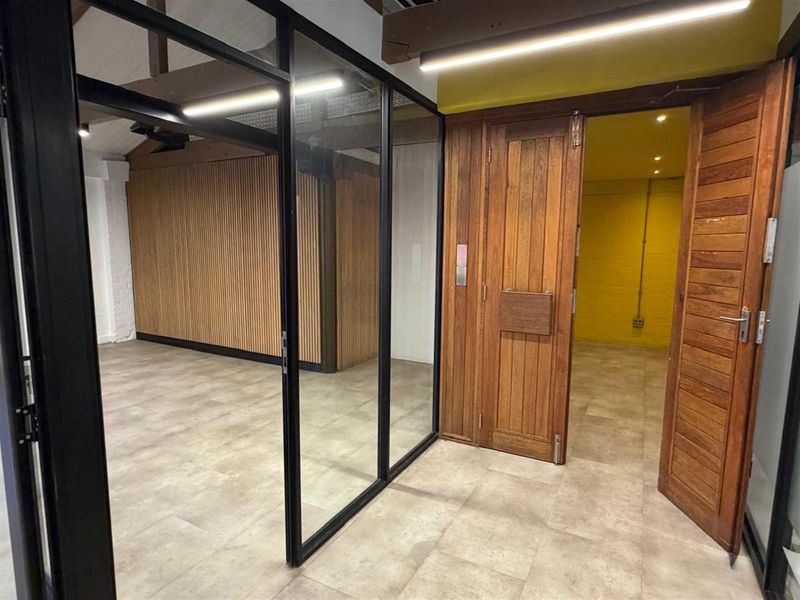 Modern office space featuring glass partitions, timber slat wall paneling, and solid wood doors, creating a professional and contemporary work environment.