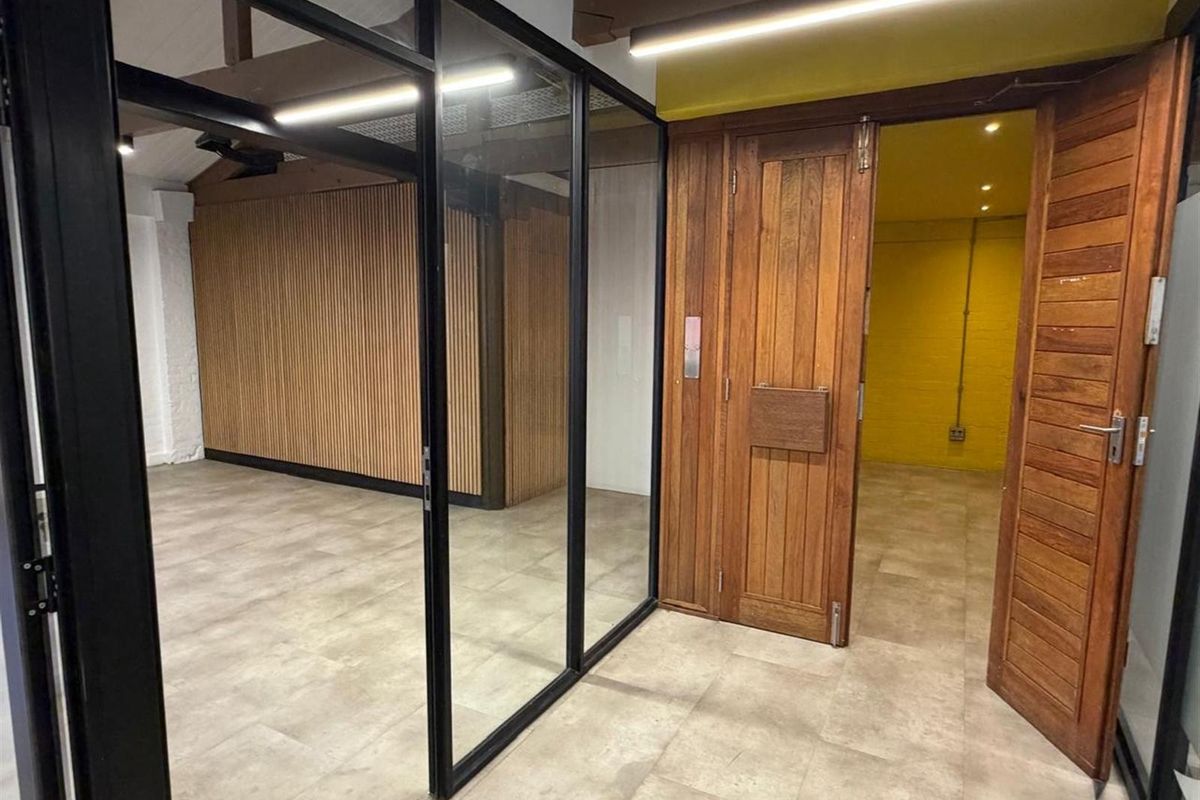 Modern office space featuring glass partitions, timber slat wall paneling, and solid wood doors, creating a professional and contemporary work environment.
