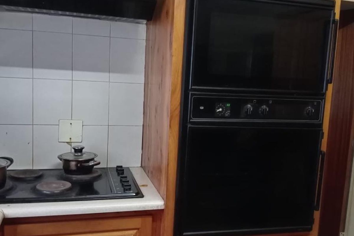 Kitchen area featuring wooden cabinetry, a built-in oven, and a black hob with an extractor fan.