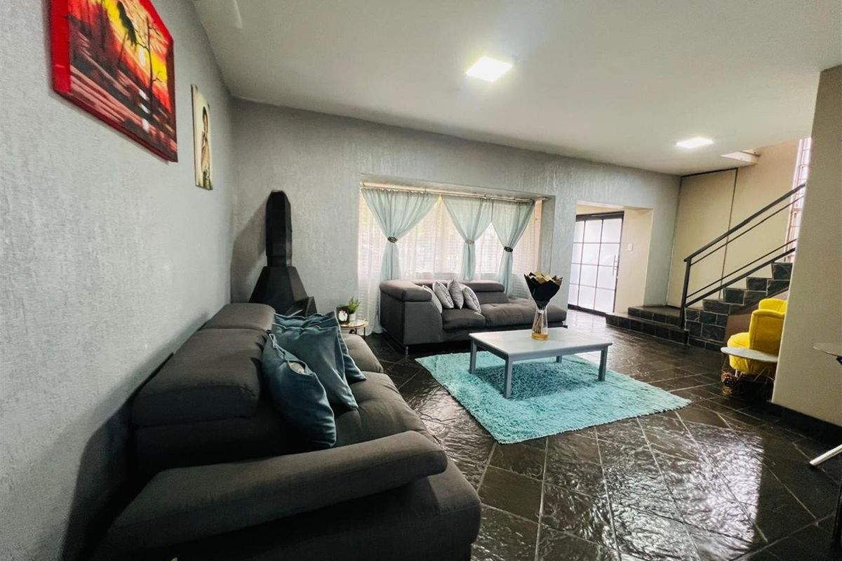 Spacious living room featuring dark tiled flooring, a built-in fireplace, and a staircase leading to the upper level.