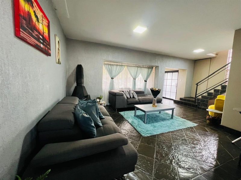 Spacious living room featuring dark tiled flooring, a built-in fireplace, and a staircase leading to the upper level.