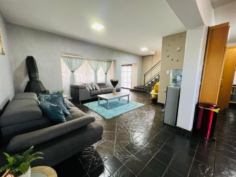 Spacious open-plan living area featuring dark slate tile flooring, a built-in fireplace, and a staircase leading to the upper level.
