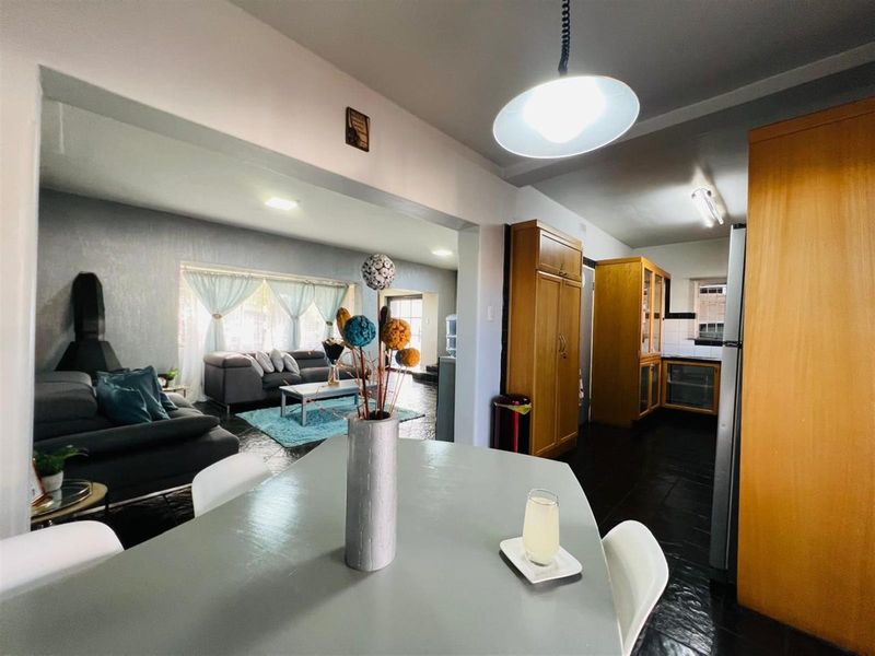 Open-plan living and dining area featuring dark tiled flooring, integrated wooden cabinetry, and a functional kitchen layout with built-in oven and hob.