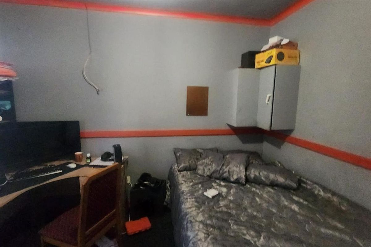 A compact bedroom featuring built-in wall cabinetry and a functional layout, currently utilized as a combined sleeping and workspace area.