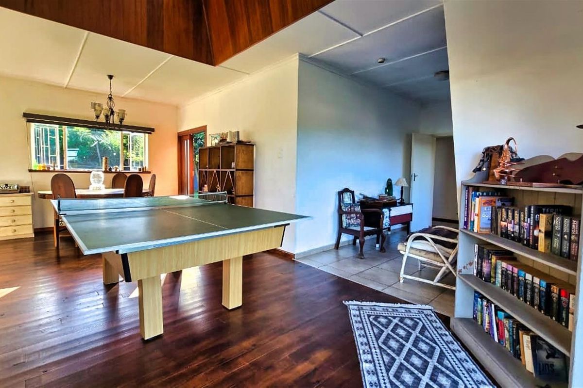 Spacious living area featuring warm timber flooring and a vaulted ceiling with wood paneling, offering a versatile layout for relaxation or recreation.