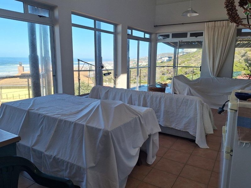 Spacious living area featuring large windows with expansive coastal views, tiled flooring, and direct access to an outdoor balcony.