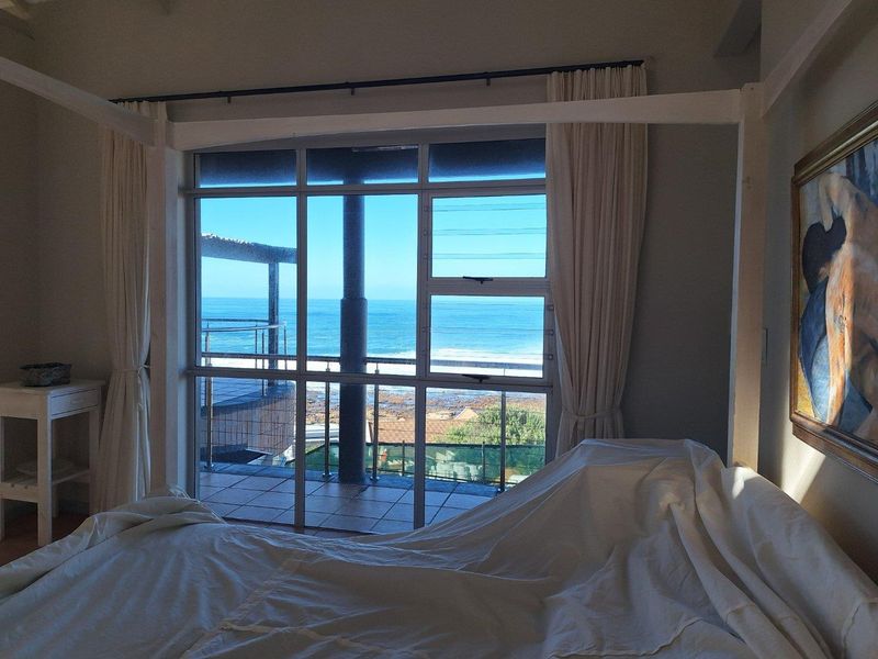 A bedroom featuring large glass sliding doors that open onto a balcony with expansive ocean views.