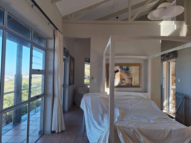 Spacious bedroom featuring high vaulted ceilings, large windows with natural light, and direct access to an outdoor balcony area.