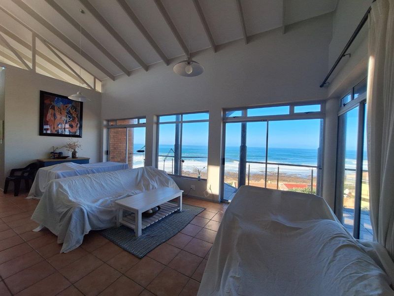 Spacious living area featuring high vaulted ceilings, tiled flooring, and large sliding glass doors opening to a scenic ocean view.