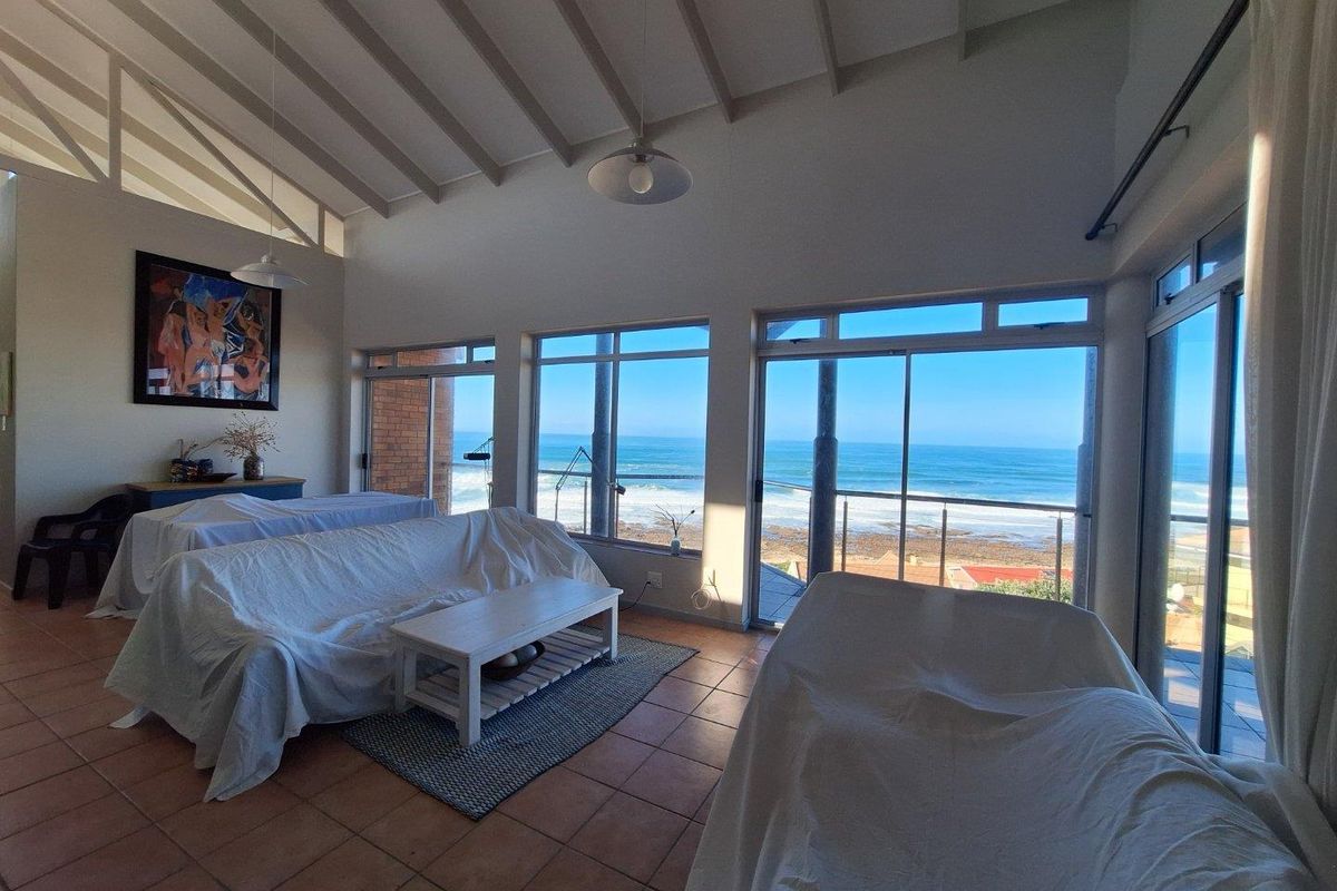 Spacious living area featuring high vaulted ceilings, tiled flooring, and large sliding glass doors opening to a scenic ocean view.
