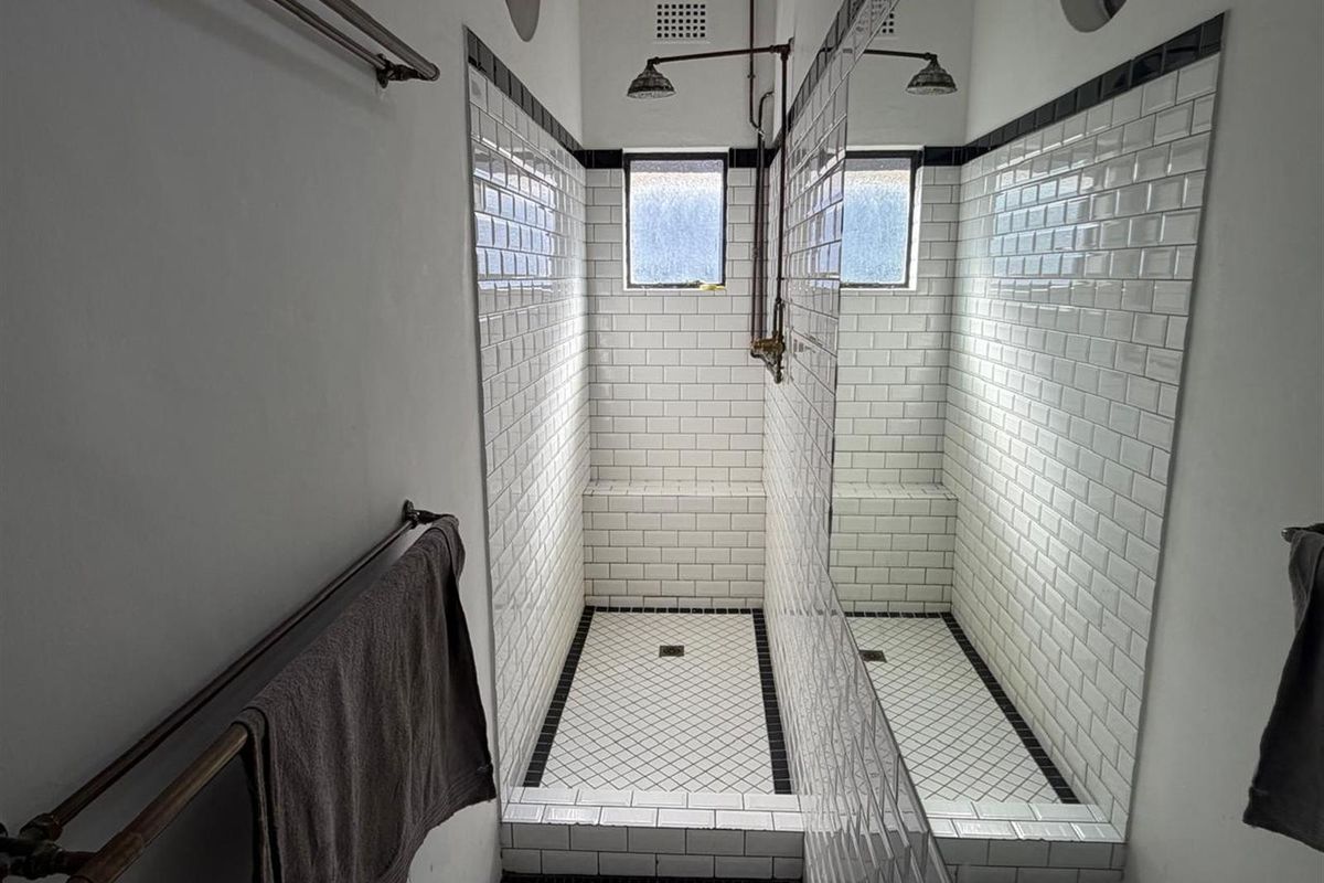 A walk-in shower featuring classic white subway wall tiles, a built-in tiled bench, and a black and white checkered floor finish.