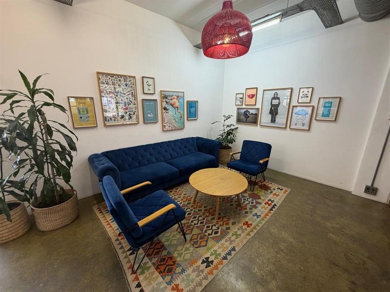 A bright office lounge area featuring polished concrete flooring, exposed industrial ceiling ducting, and a modern pendant light fixture.