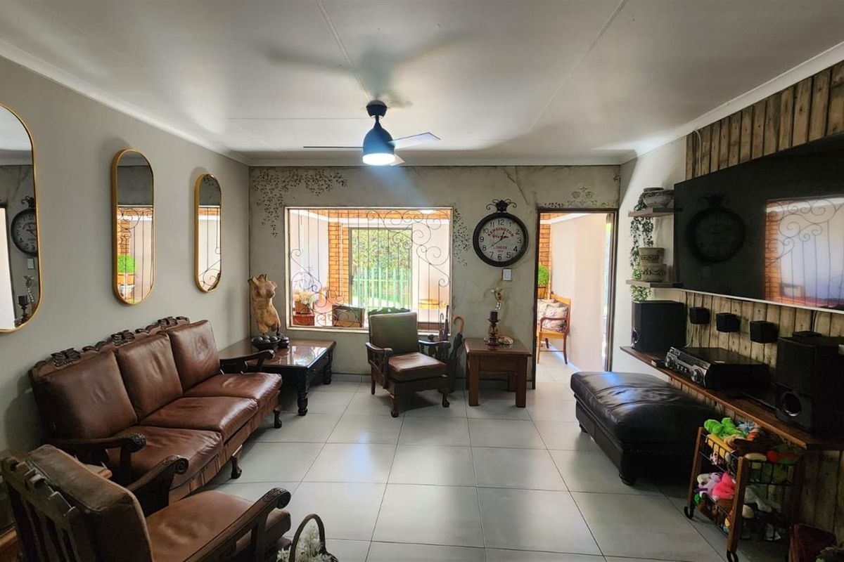 Spacious living room featuring tiled flooring, a ceiling fan, and decorative timber wall cladding, providing a comfortable and functional family space.