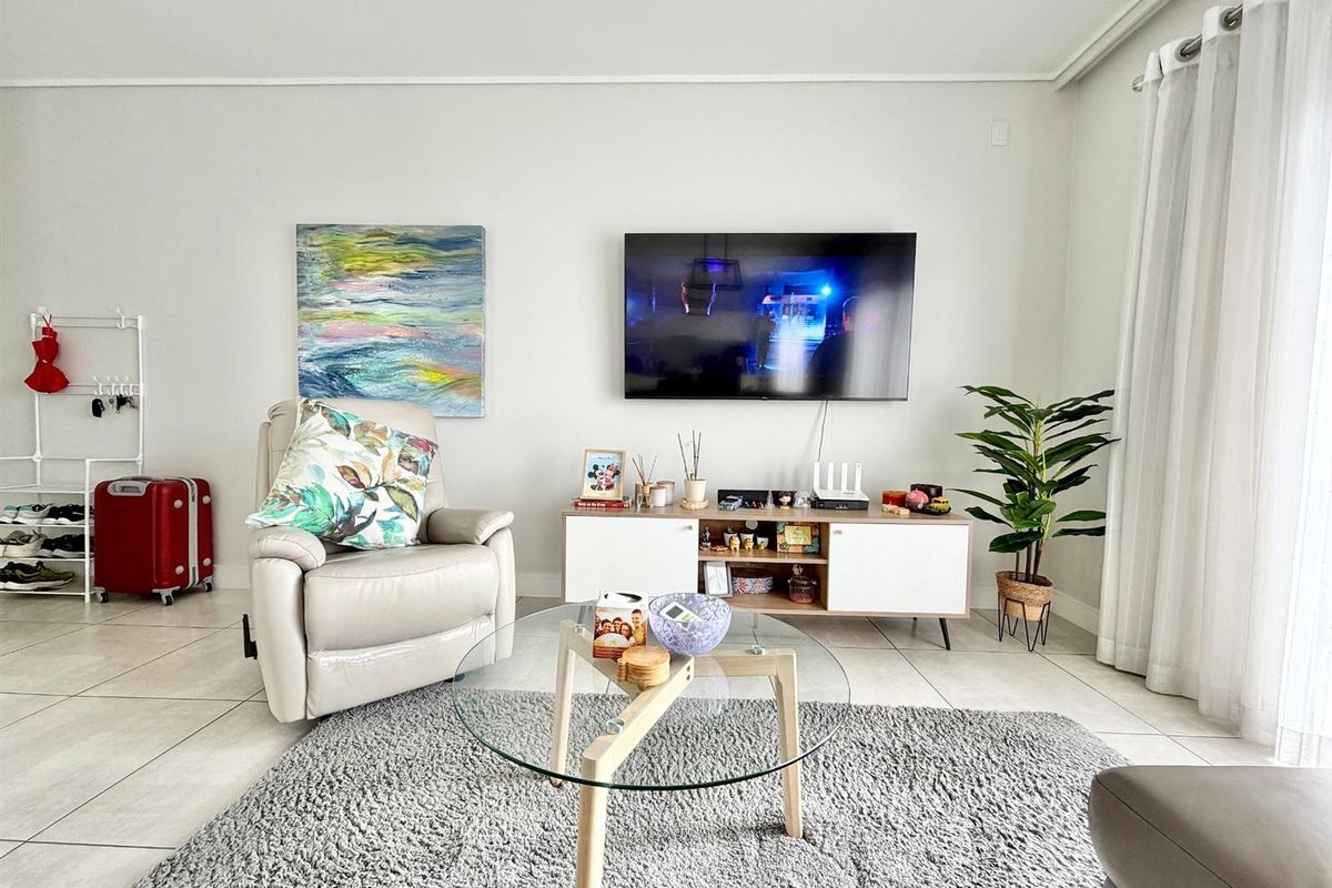 A bright and well-maintained living room featuring neutral tiled flooring and a clean, modern aesthetic.