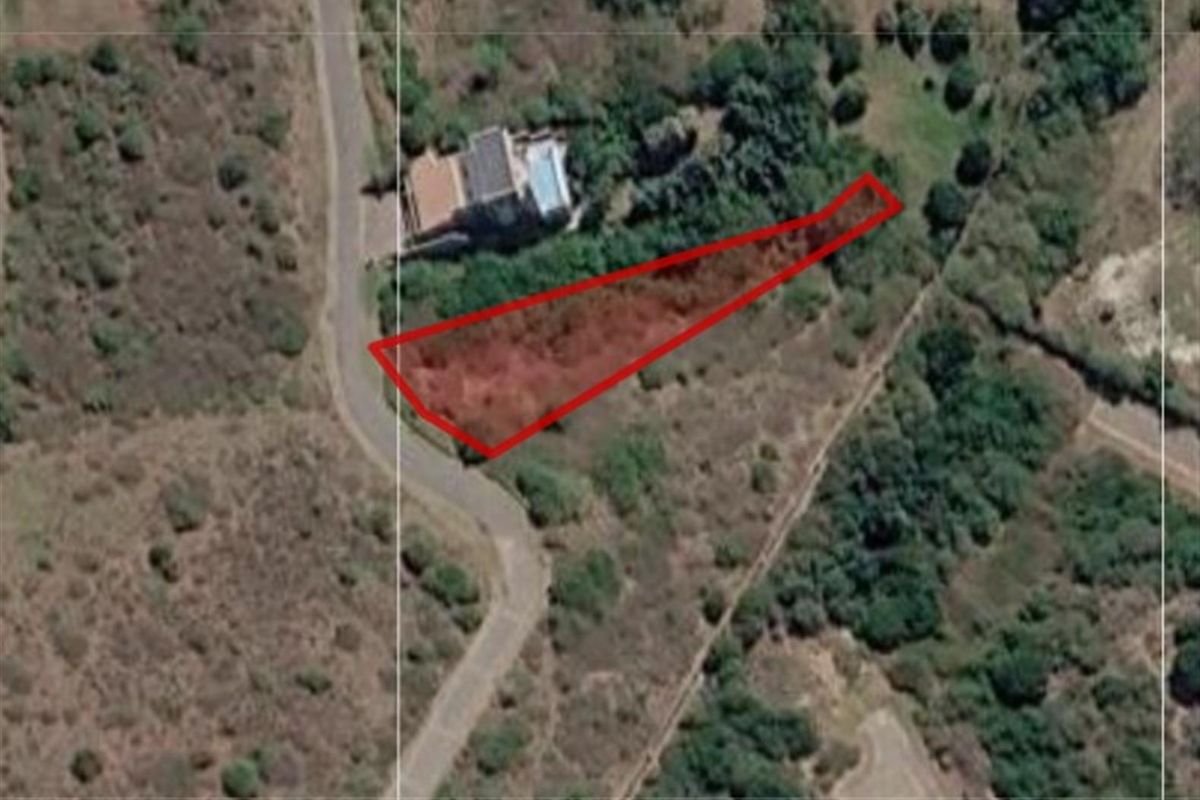 Aerial view of a vacant residential plot highlighted in red, showing its shape and proximity to local road infrastructure and surrounding vegetation.