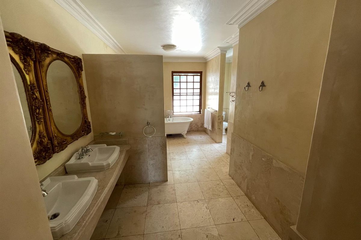 Spacious bathroom featuring a double vanity with stone countertop, a classic clawfoot bathtub, and neutral tiled flooring.
