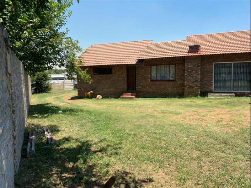 Rear view of a face brick house featuring a tiled roof, sliding door access, and a large garden area with boundary walling.