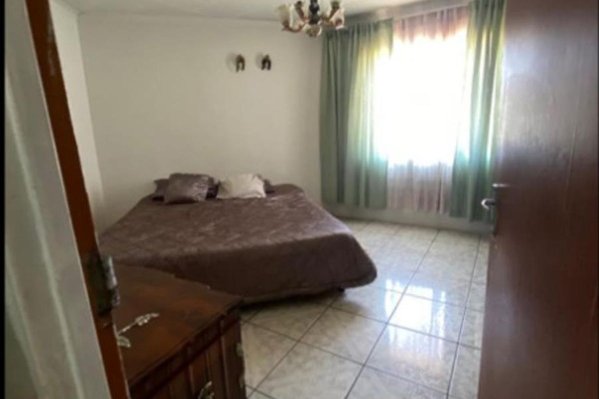 A bedroom featuring tiled flooring and a central ceiling light fixture, viewed from the doorway.