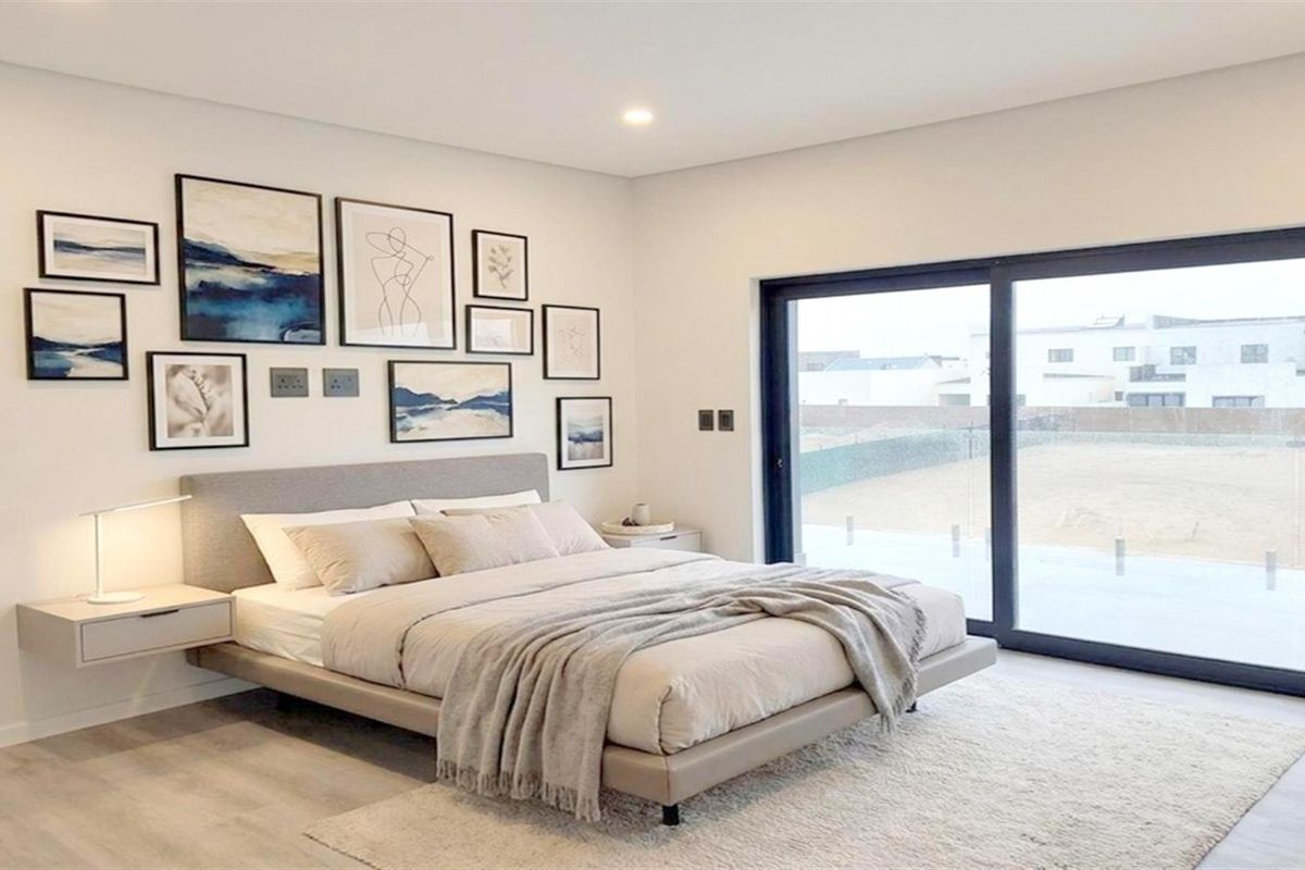 Modern bedroom featuring neutral tones, recessed lighting, and large sliding glass doors providing ample natural light and access to the exterior.
