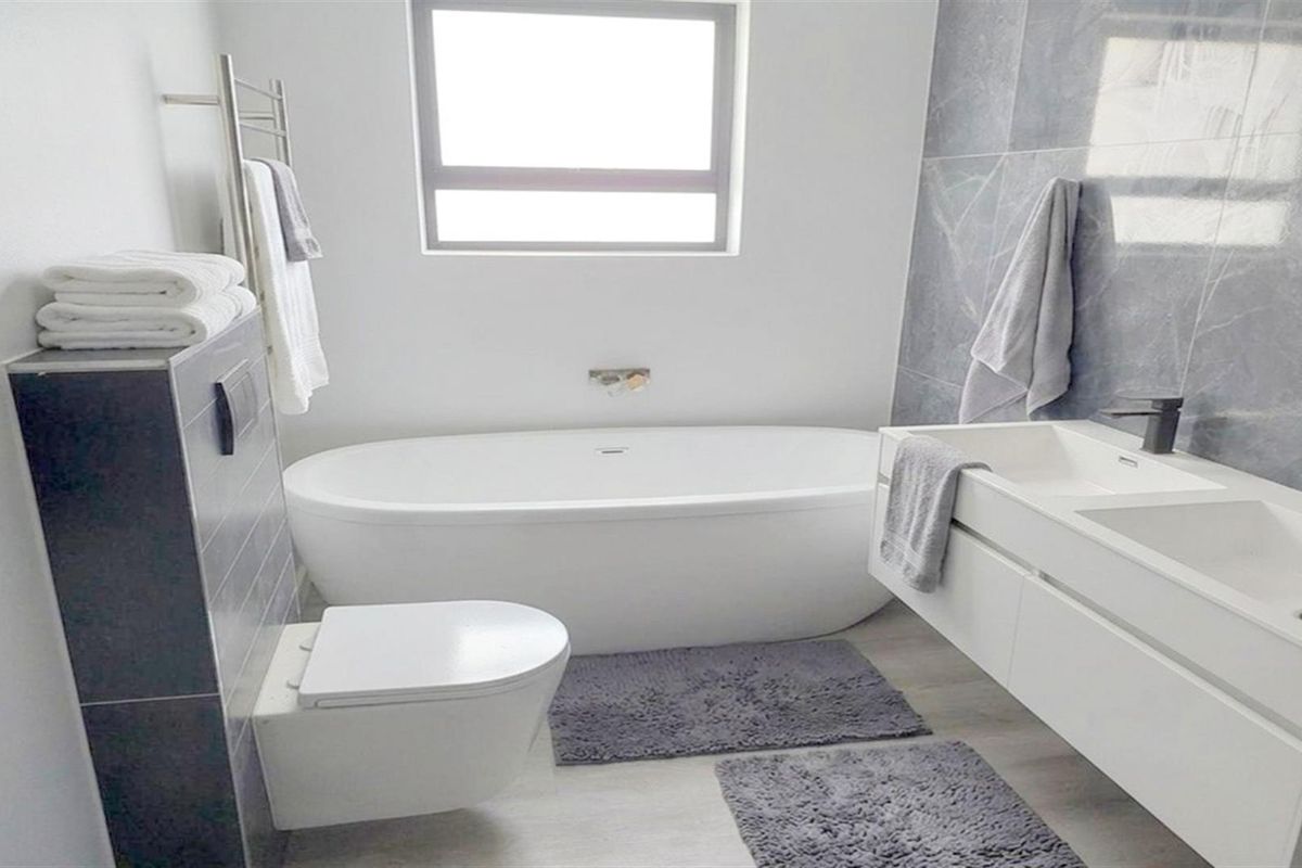Modern bathroom featuring a sleek freestanding bathtub, wall-hung toilet, and a contemporary double vanity with high-quality finishes.