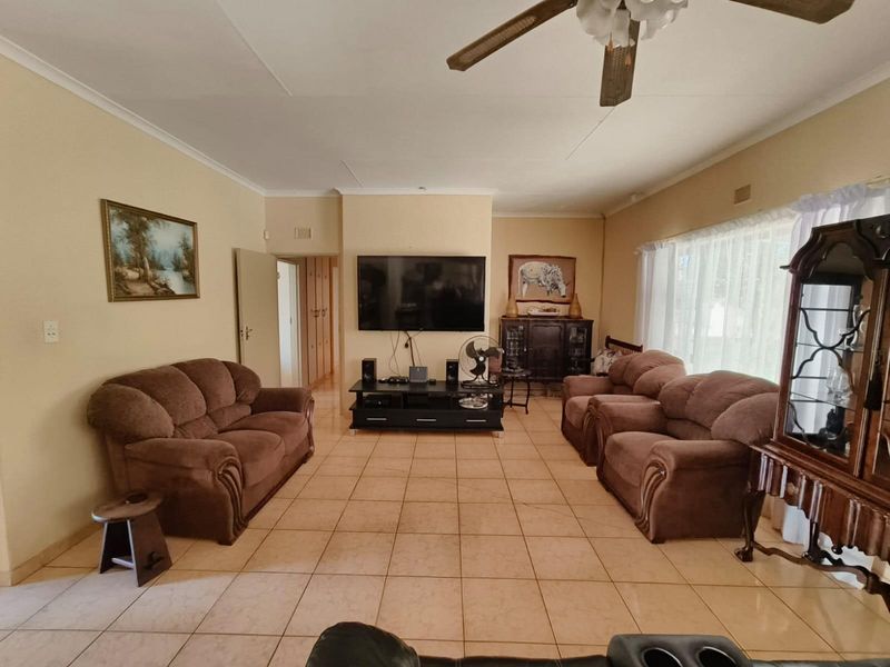 A spacious living room featuring neutral tiled flooring, a ceiling fan, and built-in storage cupboards, offering a functional and comfortable layout.