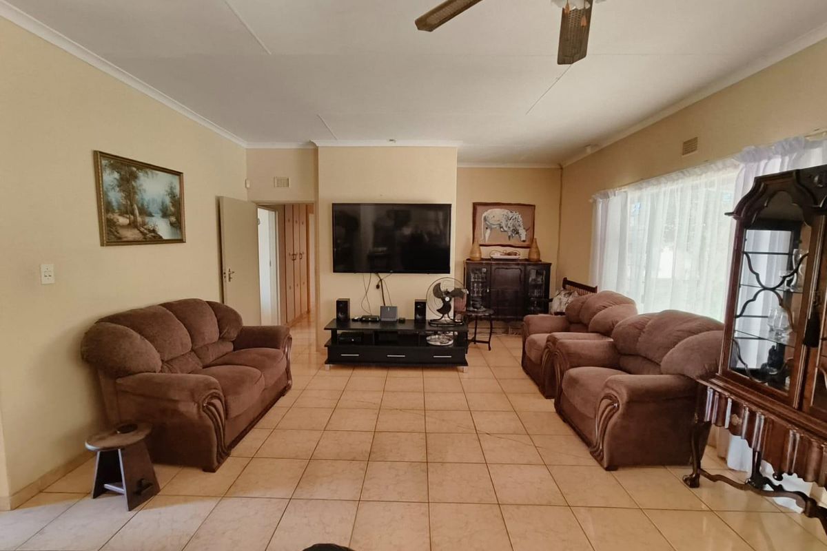 A spacious living room featuring neutral tiled flooring, a ceiling fan, and built-in storage cupboards, offering a functional and comfortable layout.