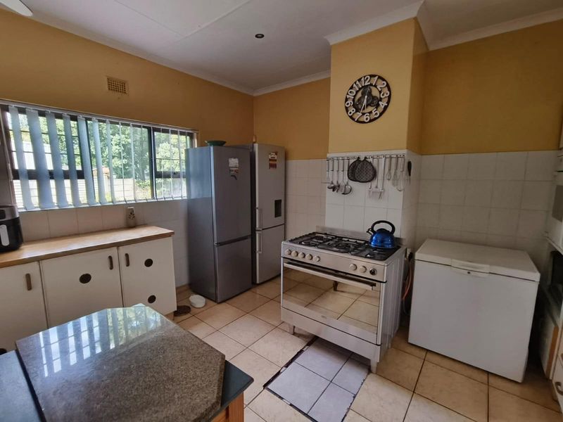 A functional kitchen featuring tiled flooring, a gas stove, and built-in cabinetry with a tiled splashback.