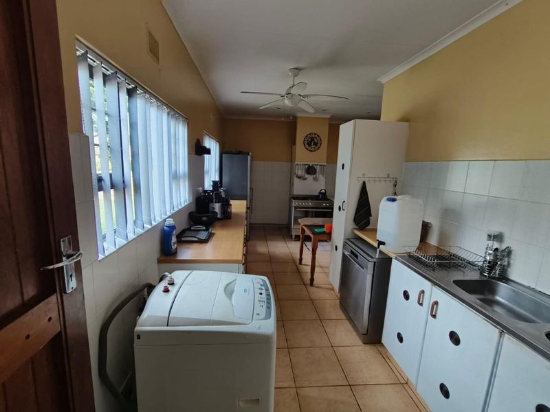 A functional kitchen featuring tiled flooring, built-in cabinetry, a stainless steel sink, and a gas stove, offering potential for modernization.