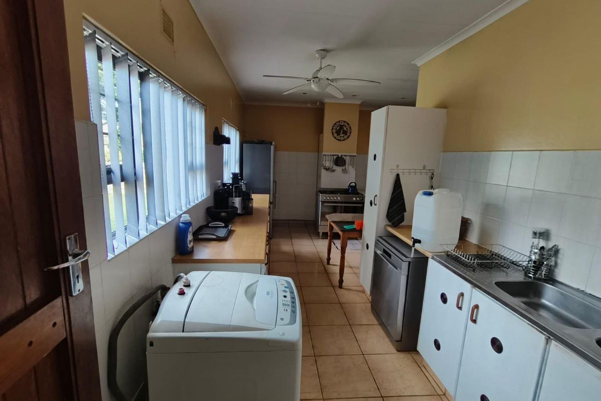 A functional kitchen featuring tiled flooring, built-in cabinetry, a stainless steel sink, and a gas stove, offering potential for modernization.
