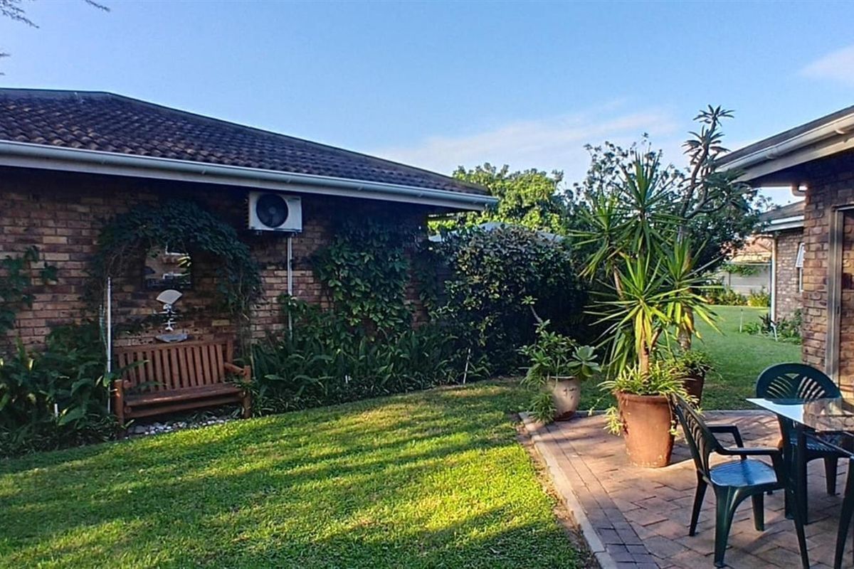 A well-maintained rear garden featuring a paved patio area, brick exterior walls, and established landscaping, providing a pleasant outdoor living space.