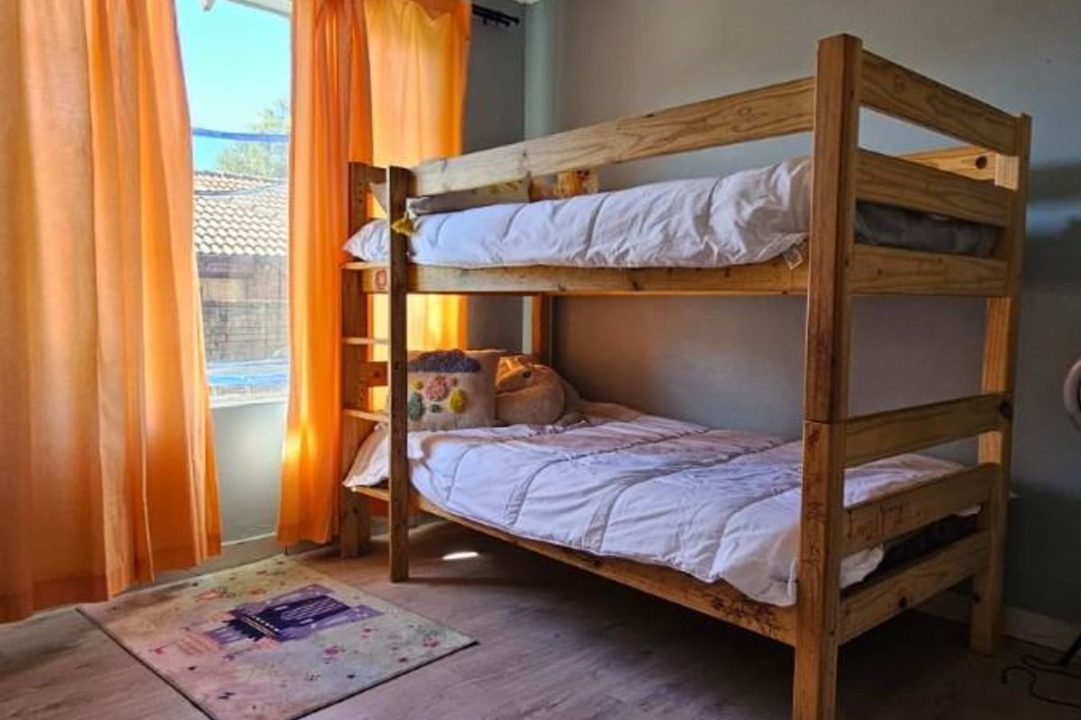 A bedroom featuring wood-look laminate flooring, decorative ceiling cornicing, and a window providing natural light.