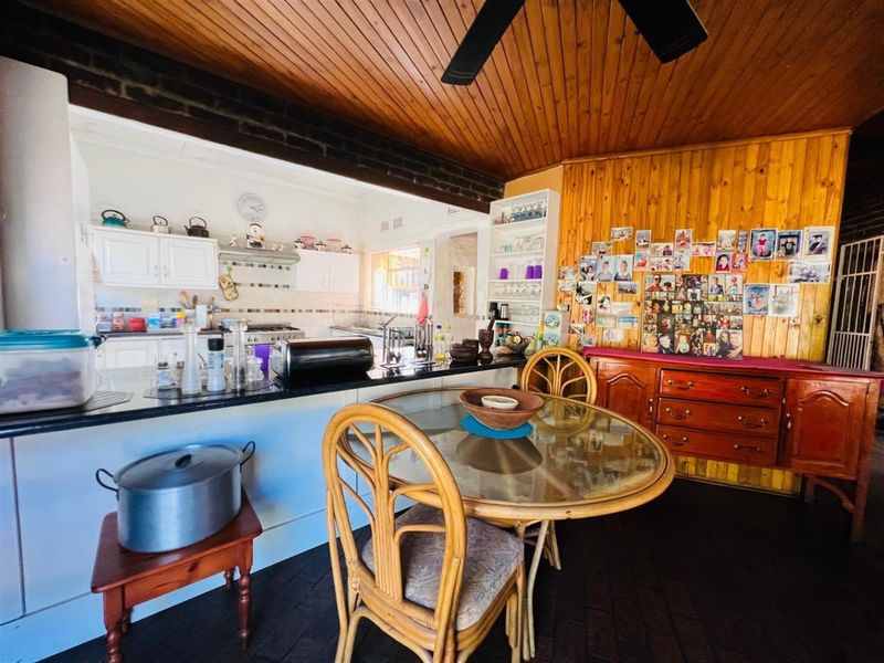 Open plan kitchen and dining area featuring a breakfast bar, wooden ceiling, and timber wall paneling.