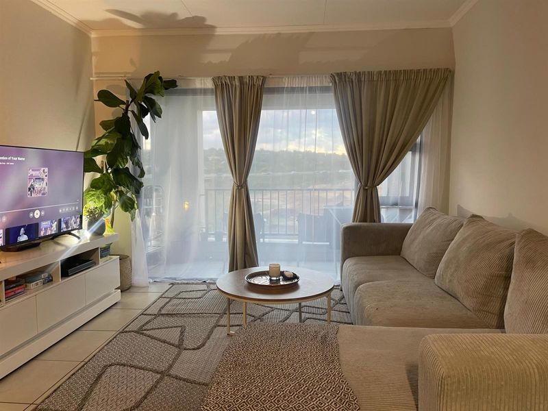 A comfortable living room featuring tiled flooring and a large sliding glass door that provides access to an outdoor balcony area.