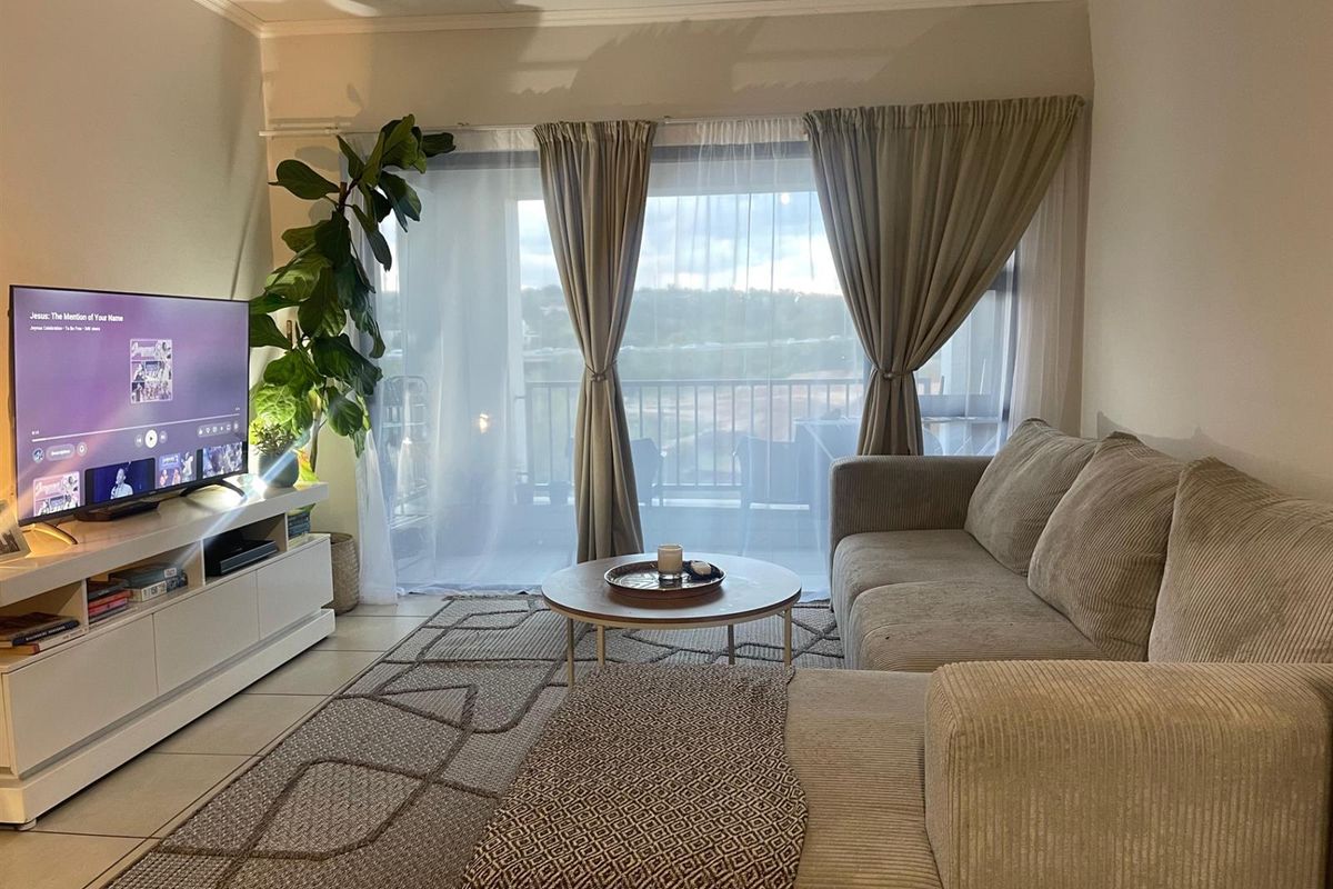 A comfortable living room featuring tiled flooring and a large sliding glass door that provides natural light and access to the balcony.