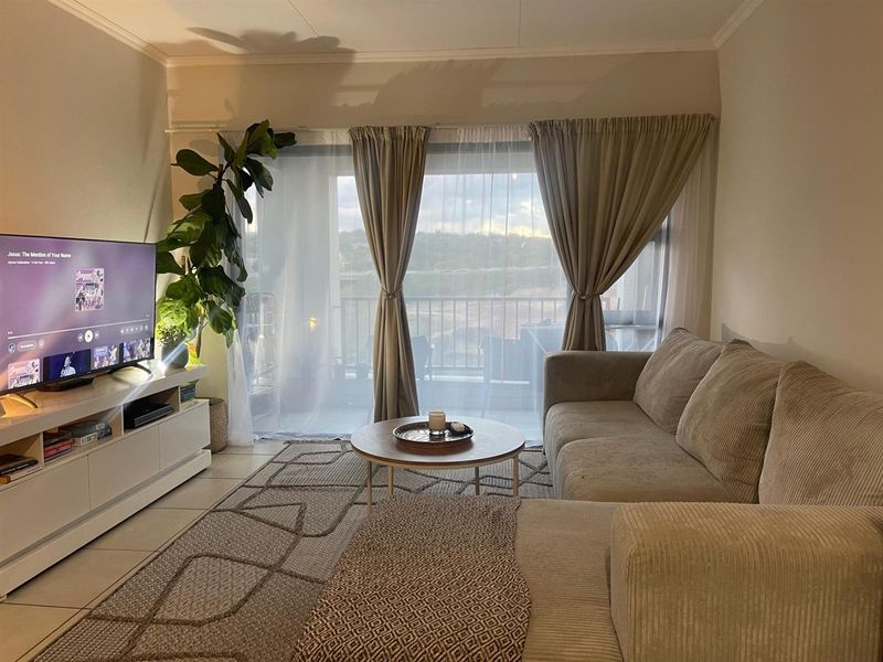 A comfortable living room featuring tiled flooring and a large sliding glass door that provides access to an outdoor balcony area.
