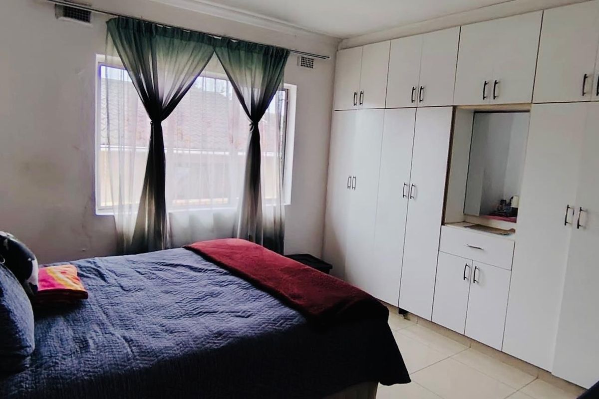 A bedroom featuring extensive built-in white cabinetry with integrated vanity and tiled flooring.