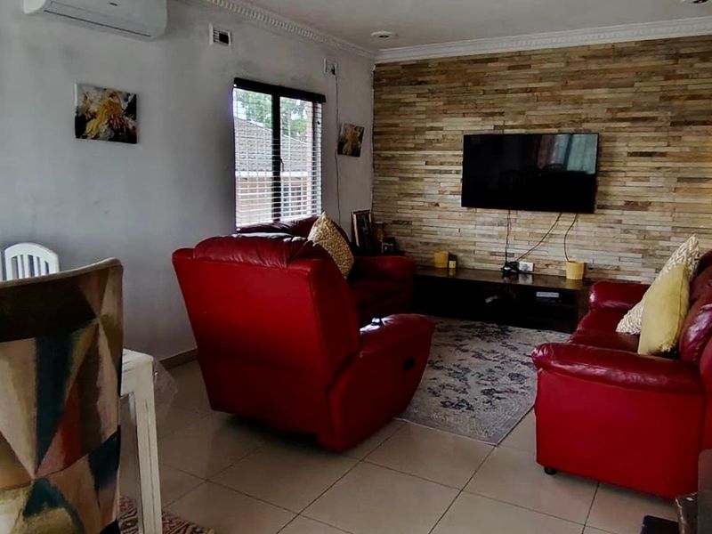 Open plan living and dining area featuring a textured stone feature wall, tiled flooring, and a wall-mounted air conditioning unit.