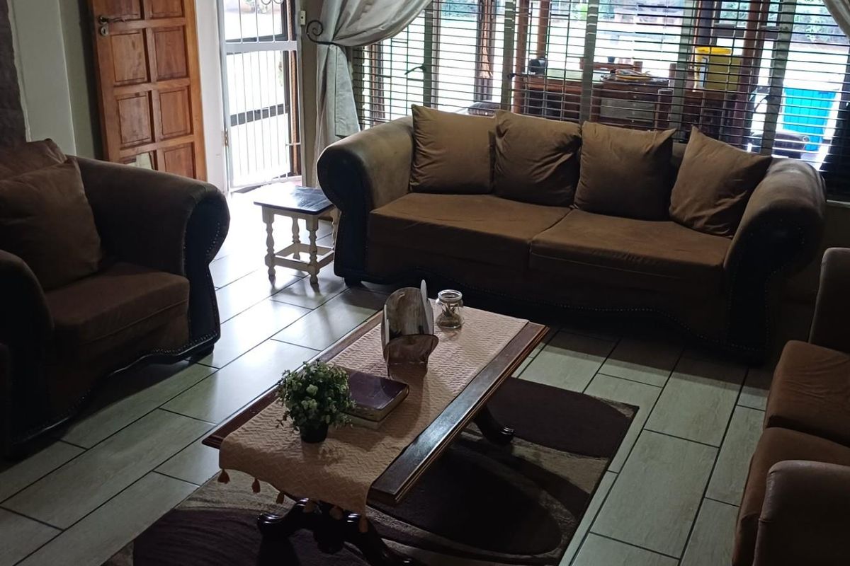 A comfortable living room featuring tiled flooring, a built-in fireplace, and large windows with blinds, providing ample natural light.