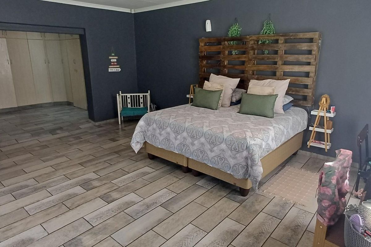 Spacious bedroom featuring wood-look tile flooring, dark accent walls, and integrated built-in cupboards in a recessed alcove area.