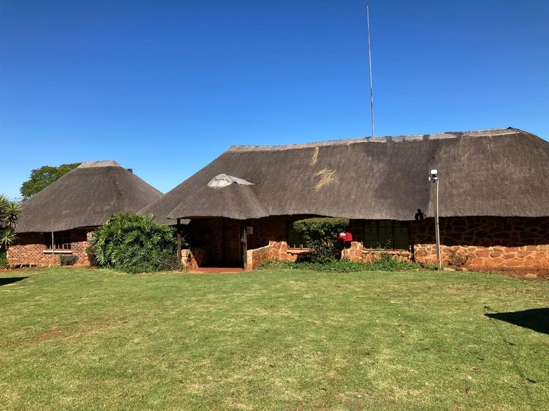A traditional stone-built small holding residence featuring a classic thatched roof, set within a spacious, well-maintained garden area.