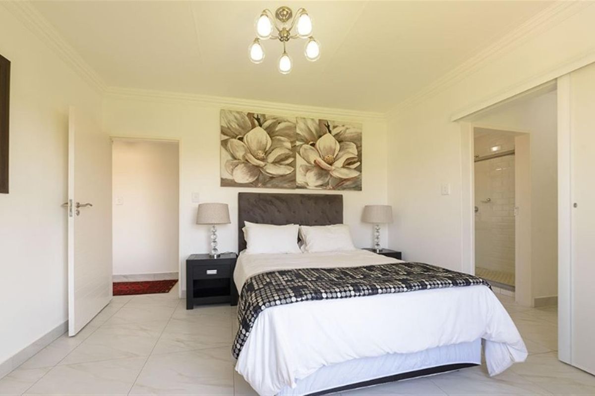 A well-maintained bedroom featuring tiled flooring, crown molding, and an en-suite bathroom access.