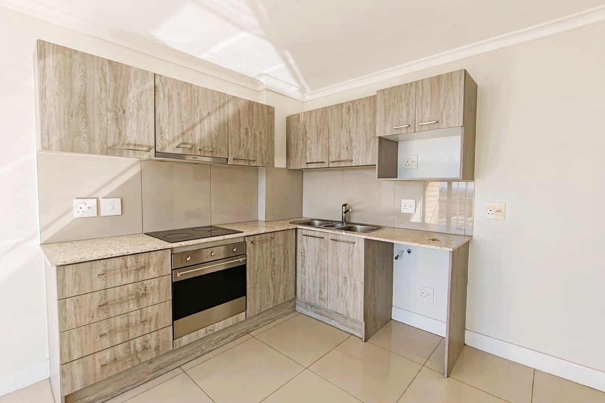 Modern kitchen featuring light wood-grain cabinetry, granite countertops, a built-in electric oven and hob, and tiled flooring.