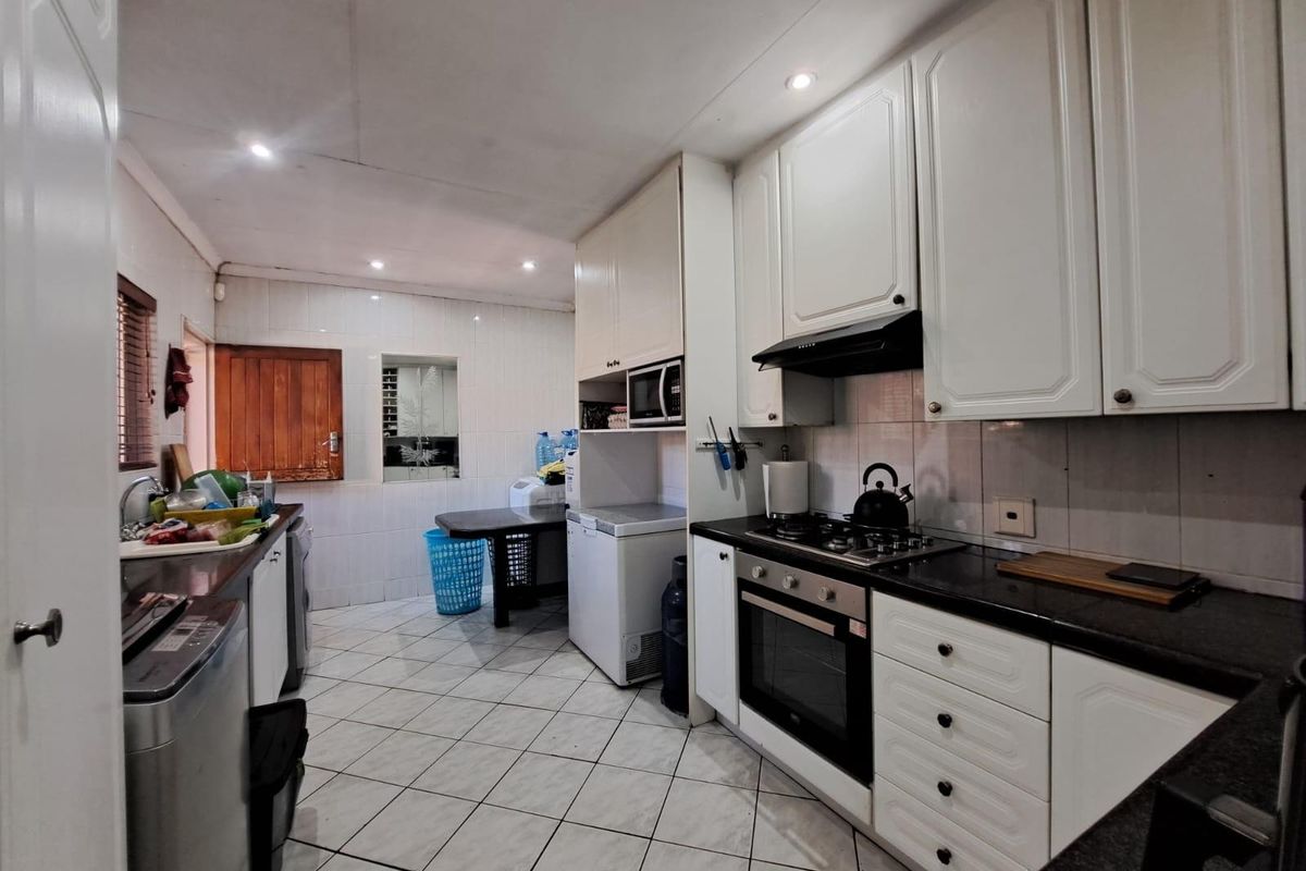 Functional kitchen featuring white cabinetry, granite countertops, built-in oven, gas hob, and tiled flooring with a practical layout for daily meal preparation.