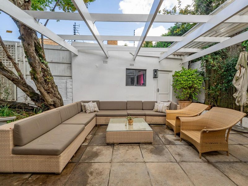 A covered outdoor patio area featuring a white timber pergola, paved flooring, and direct access to the rear of the property.