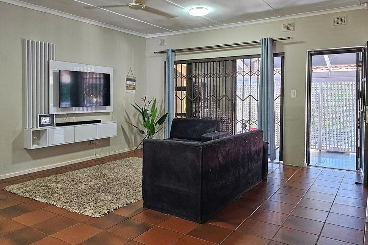 Spacious living room featuring tiled flooring, a built-in media console, and sliding glass doors providing access to the outdoor patio area.