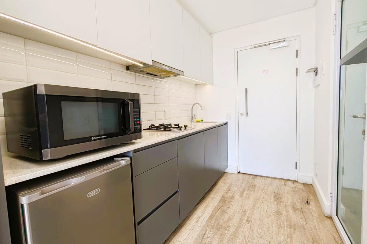 Modern compact kitchen featuring sleek cabinetry, integrated gas hob, extractor fan, and subway tile backsplash with under-cabinet lighting.