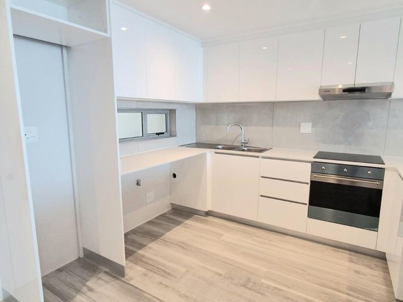 Modern kitchen featuring white high-gloss cabinetry, integrated oven, electric cooktop, stainless steel extractor fan, and light-toned wood-look tile flooring.