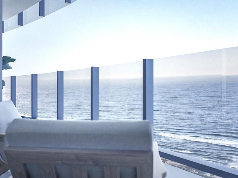 A modern balcony featuring a sleek glass balustrade with metal supports, offering expansive, unobstructed ocean views.