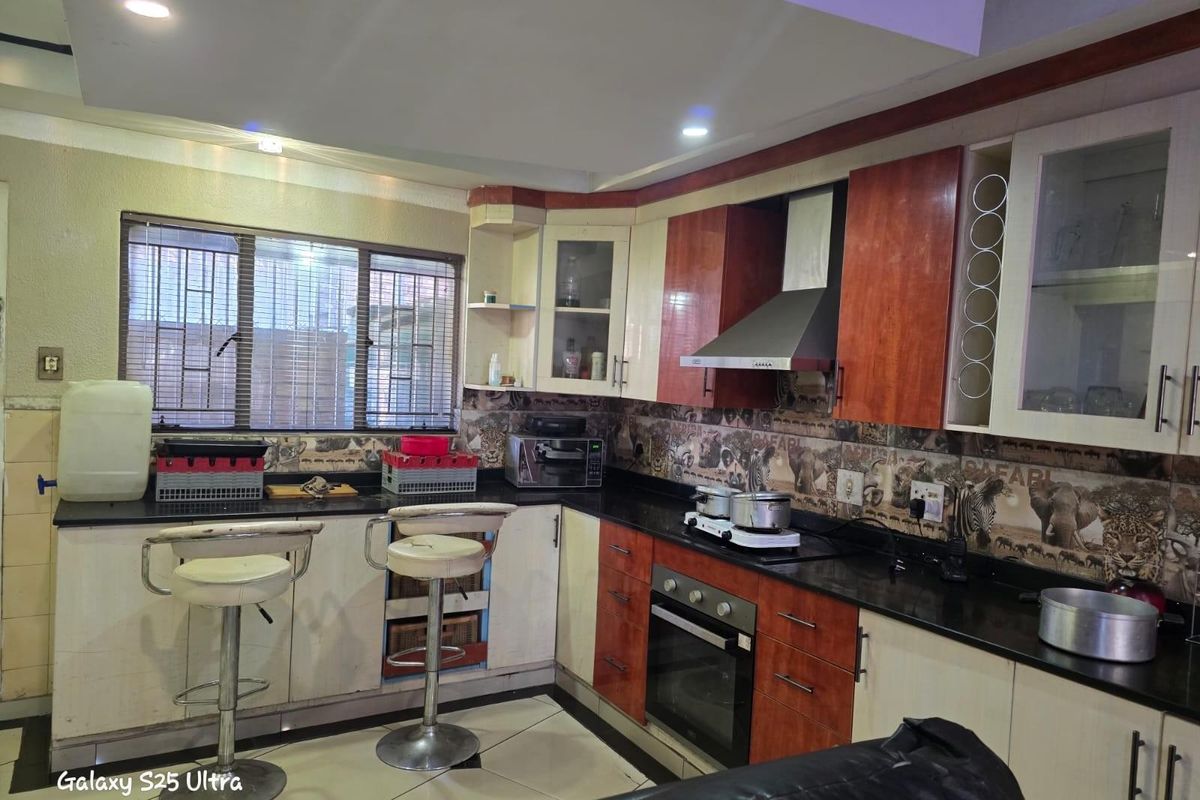 A functional kitchen featuring dark granite countertops, two-tone cabinetry, a built-in oven, and a stainless steel extractor fan.