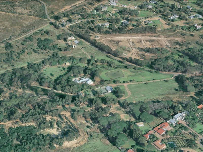 An aerial view of a large residential land plot featuring established trees, open green spaces, and existing structures within a semi-rural neighborhood setting.